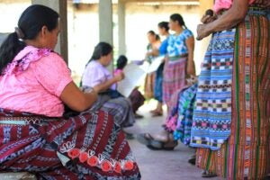 Indigenous Guatemalan women wearing traditional dresses while weaving